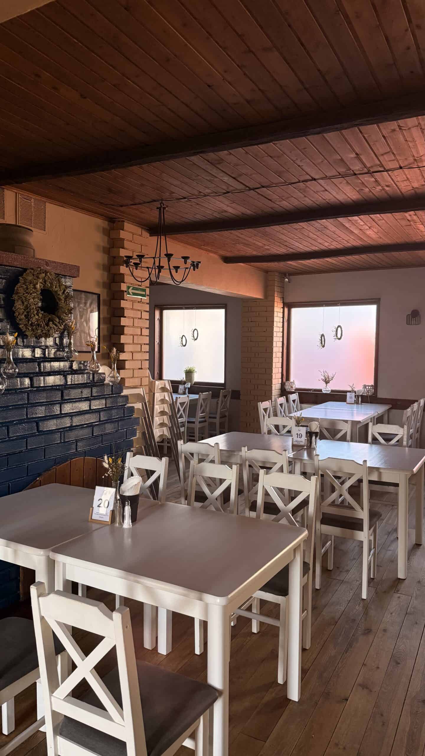 Rustykalne wnętrze restauracji Gospoda u Chłopa we Władysławowie – ceglana ściana, drewniany sufit i nakryte stoły